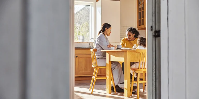 A nurse sits with a mother and child reviewing an individualized care plan pediatric home health GAPP Georgia document at their kitchen table