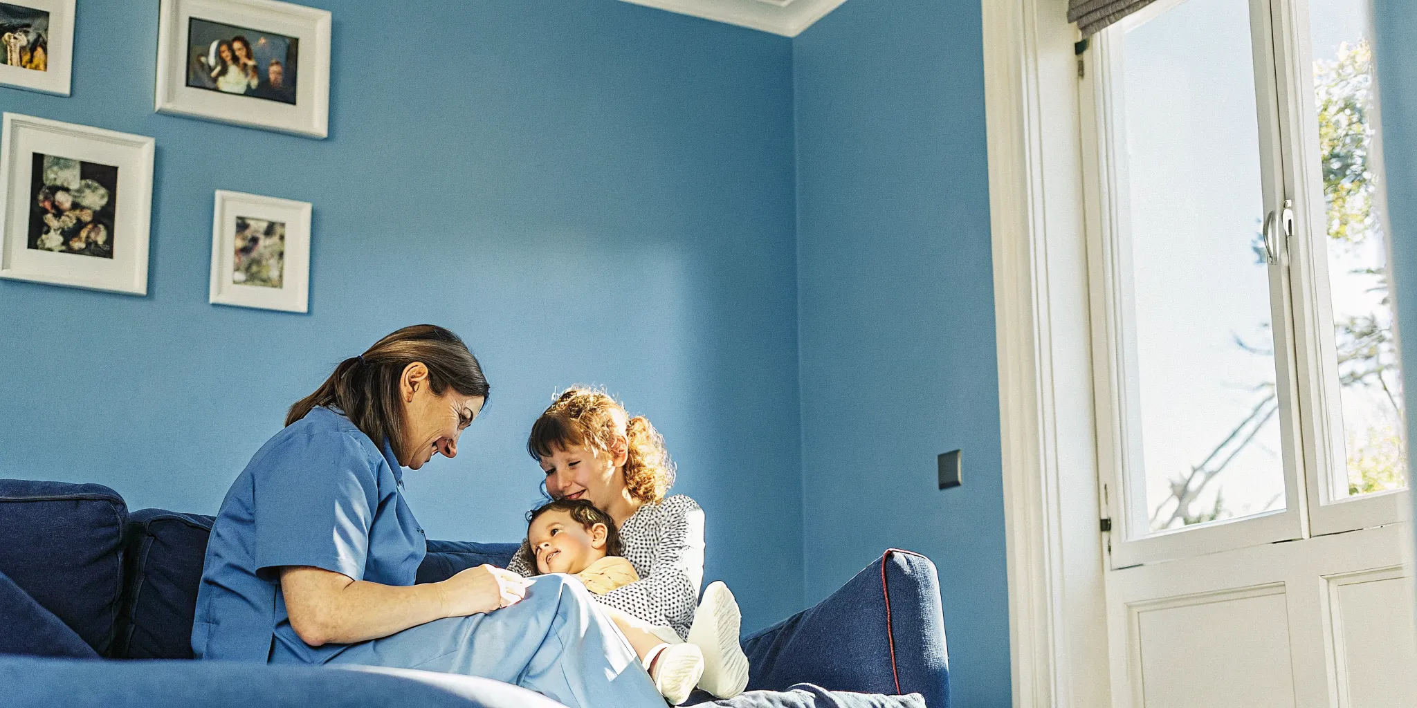 Pediatric nurse caring for a child at home with family nearby in a warm, comfortable setting